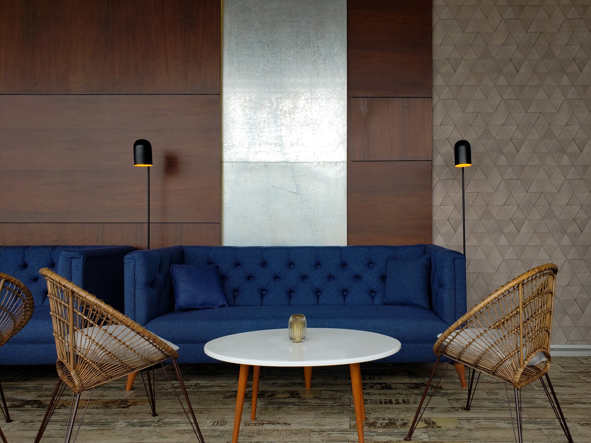 Una sala de estar con un sofá azul, sillas y una mesa.