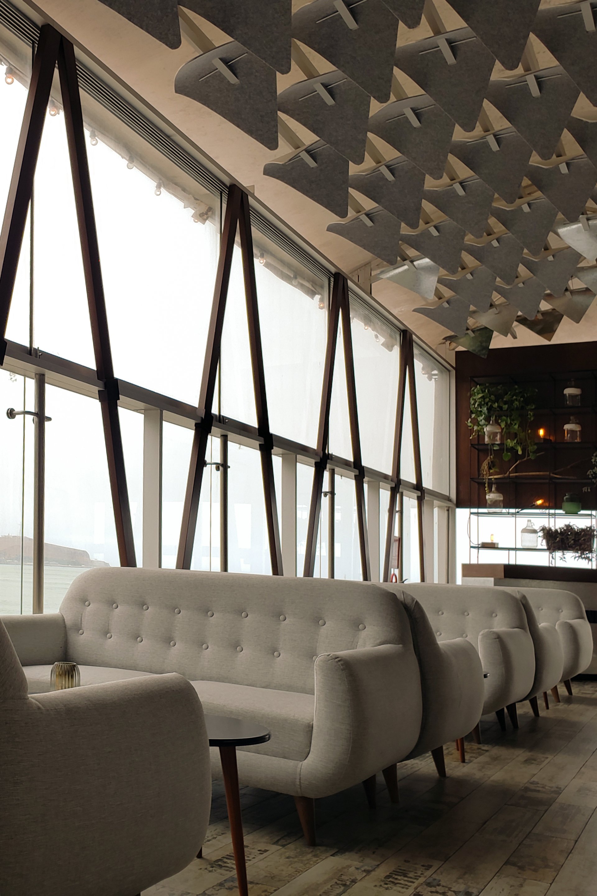 Una fila de sillas blancas y un sofá en una habitación con muchas ventanas.