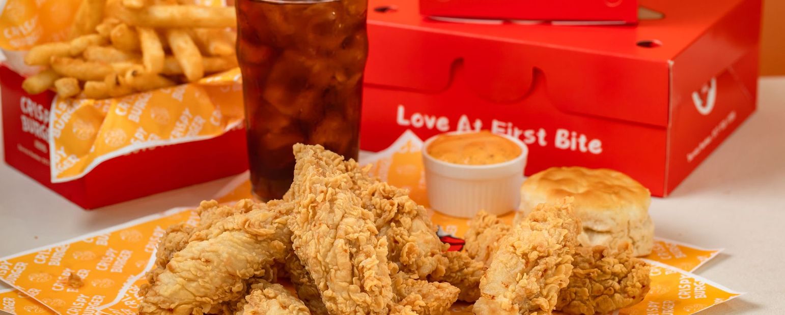 Fried chicken pieces with dipping sauce and red fast-food boxes on a table