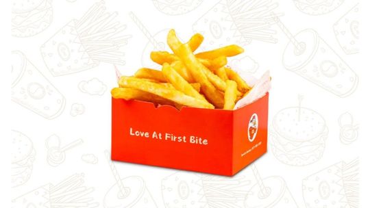 Orange fries box with golden French fries on a white patterned background