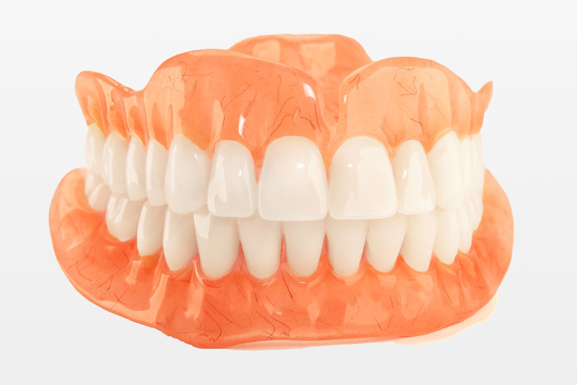 A close up of a full denture with white teeth on a white background.