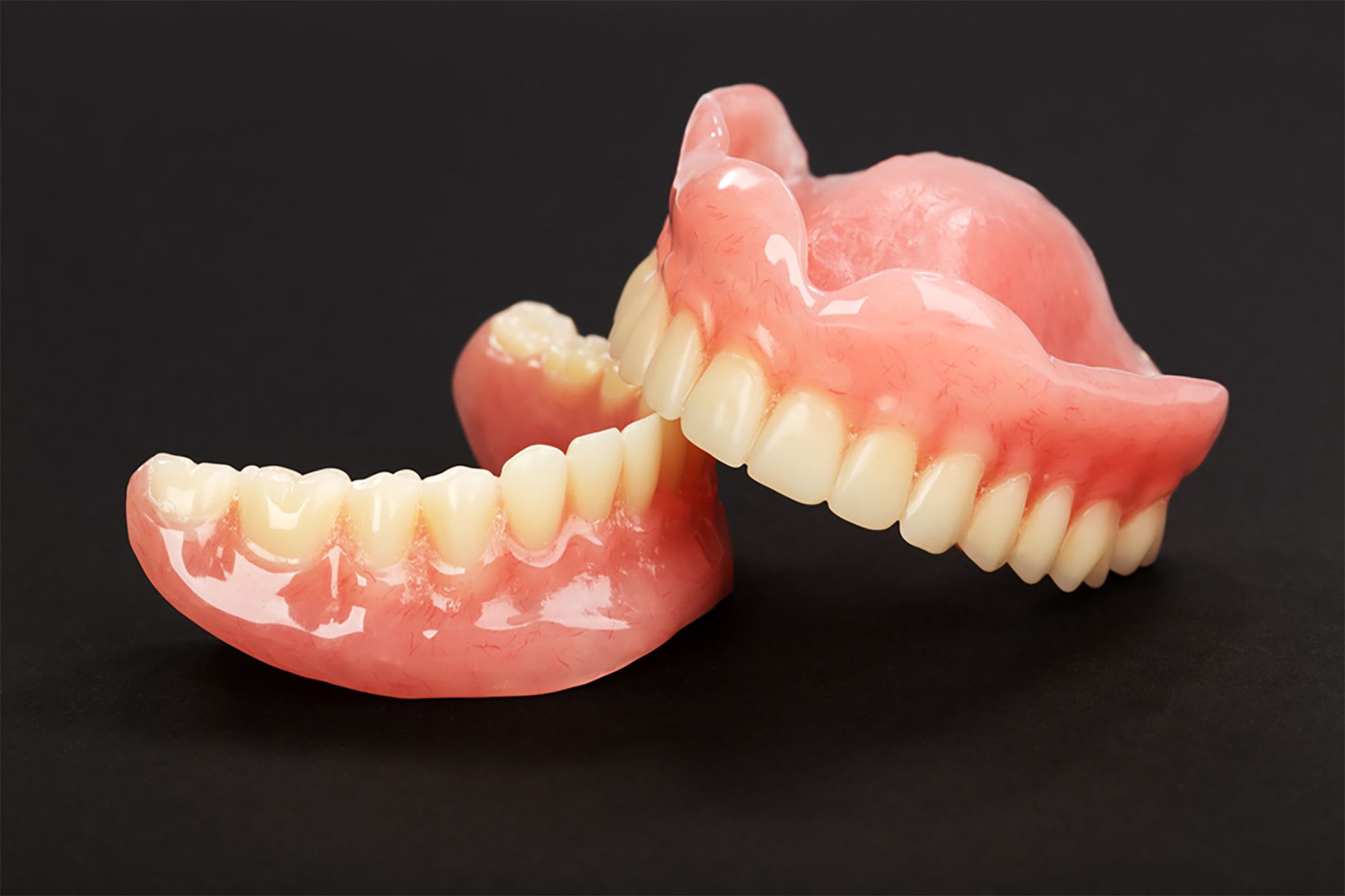 A pair of dentures are sitting on a black surface.