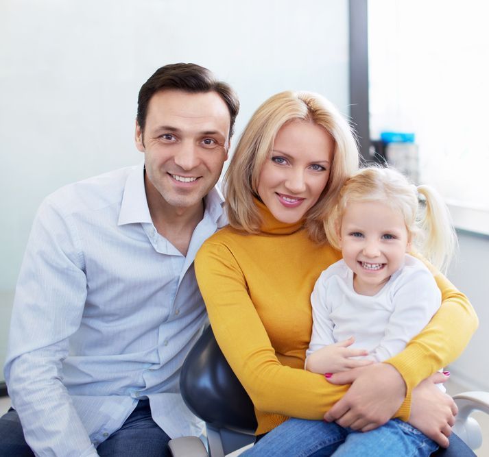 A family posing for a picture in a dental chair