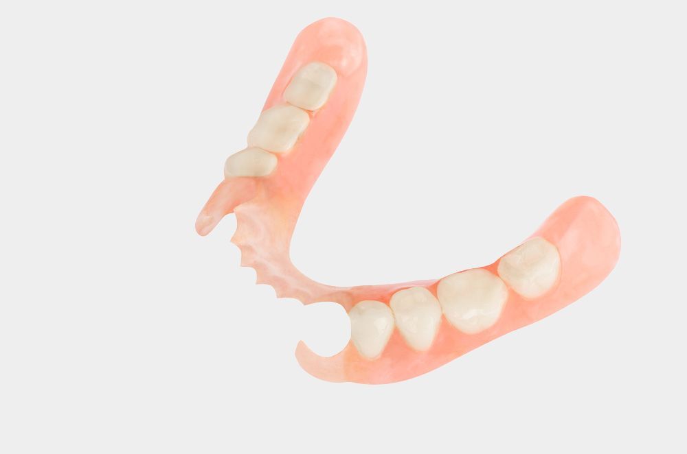A close up of a denture with teeth on a white background.