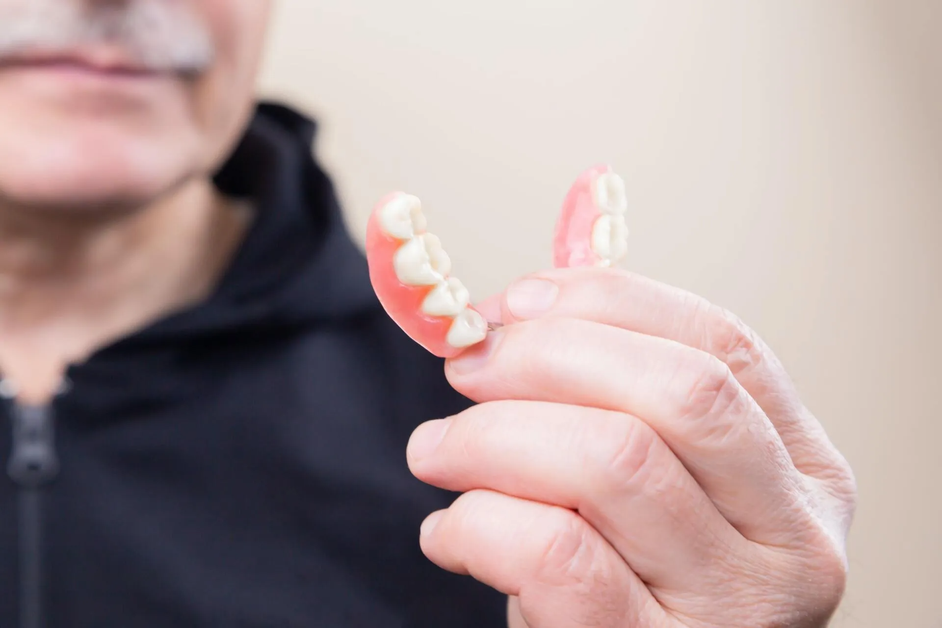 A man is holding a denture in his hand.