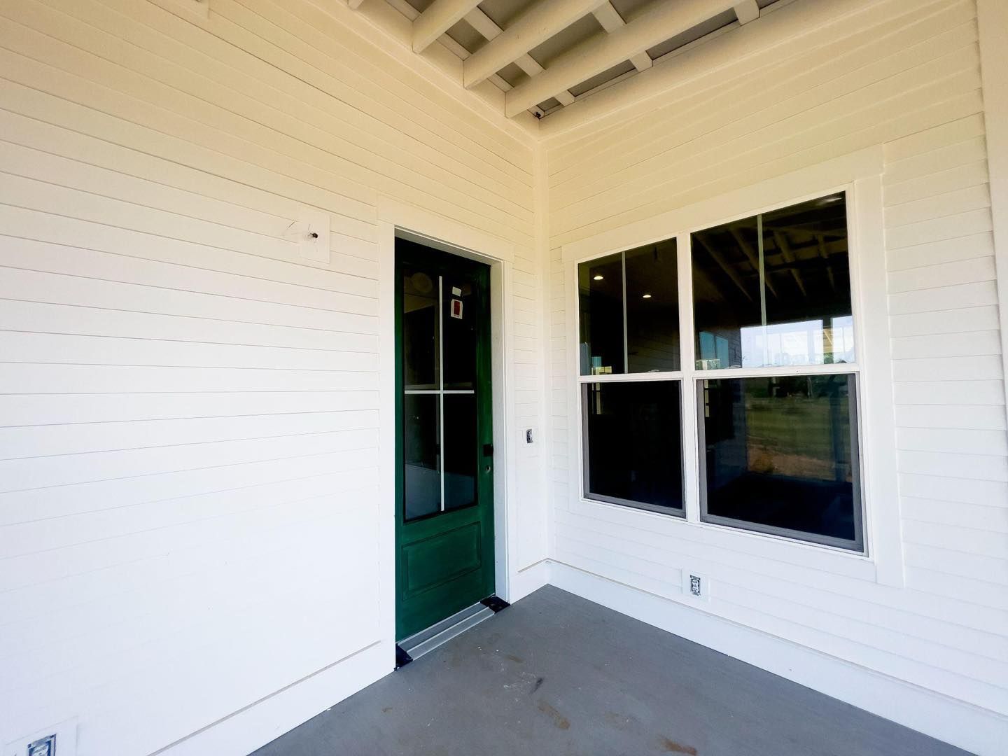White porch exterior with green door and windows.