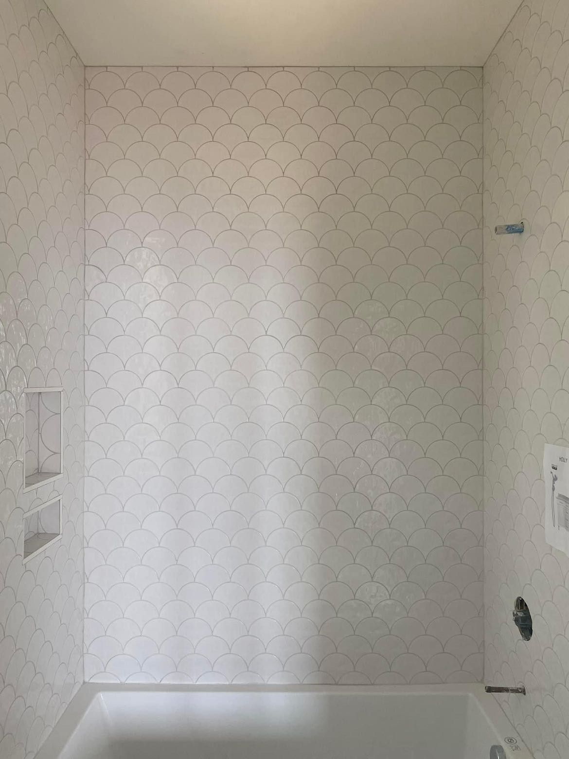 White tile shower enclosure with niche and fixtures.