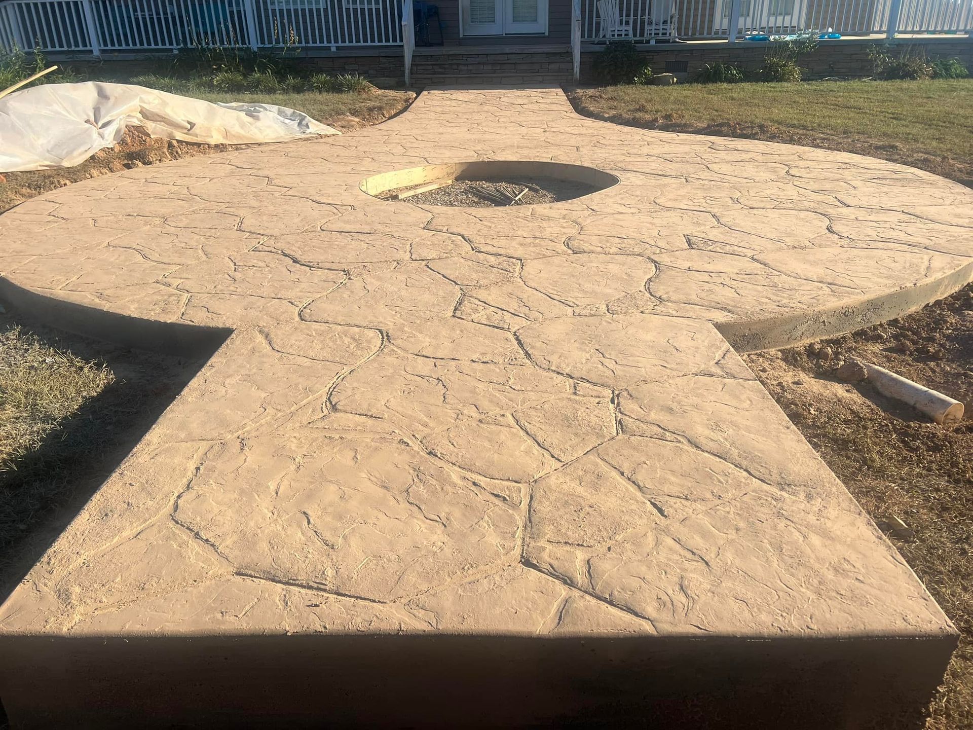 Stamped concrete walkway and patio with irregular stone pattern leading to a house.