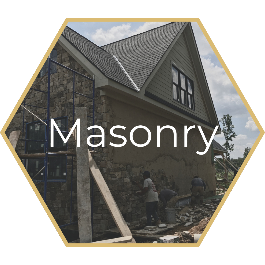 Masonry construction site with workers applying stone to a house exterior.