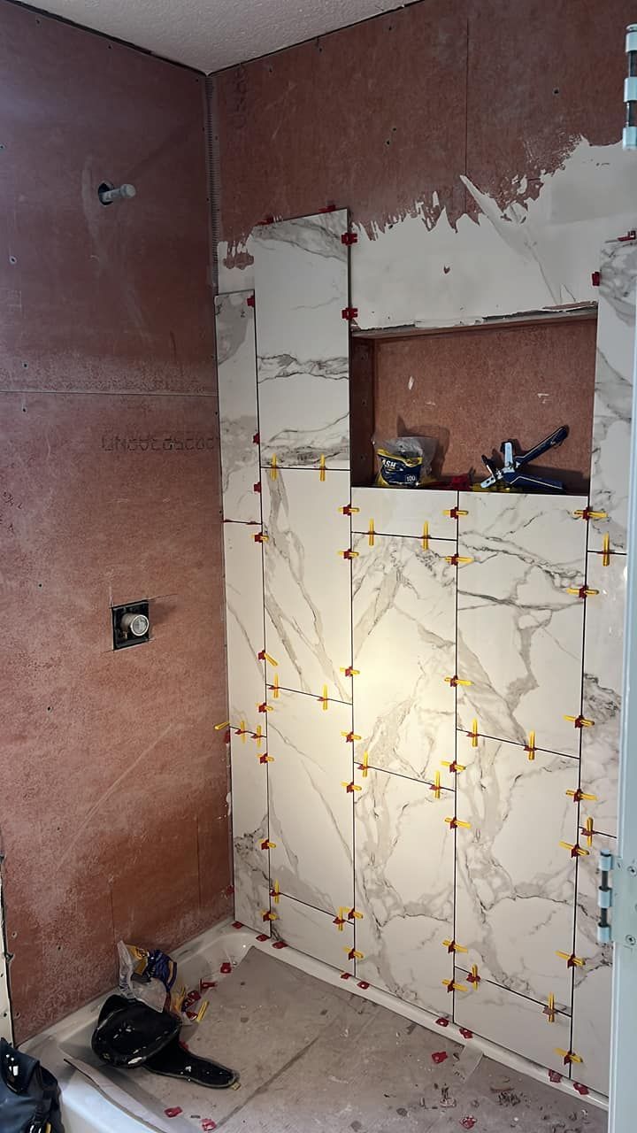 Bathroom wall under construction, tiling partially installed with tile spacers.