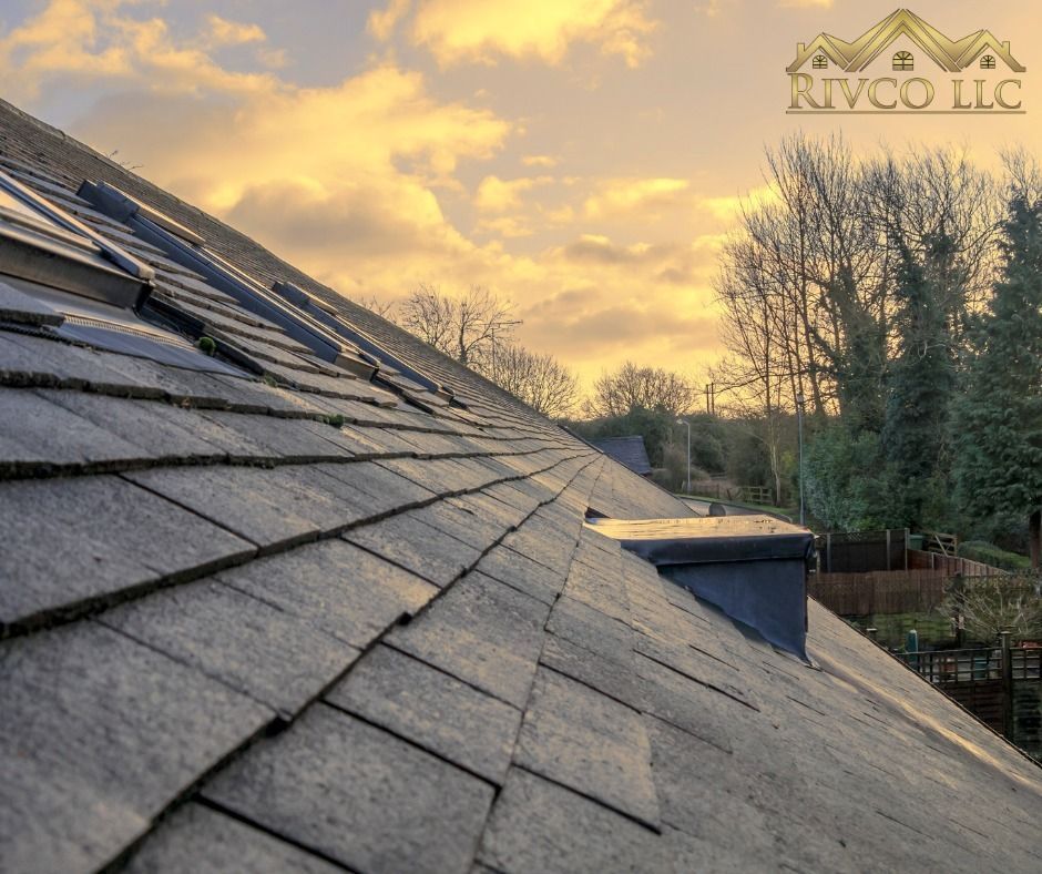 A gray shingled roof with a chimney against an overcast sky.