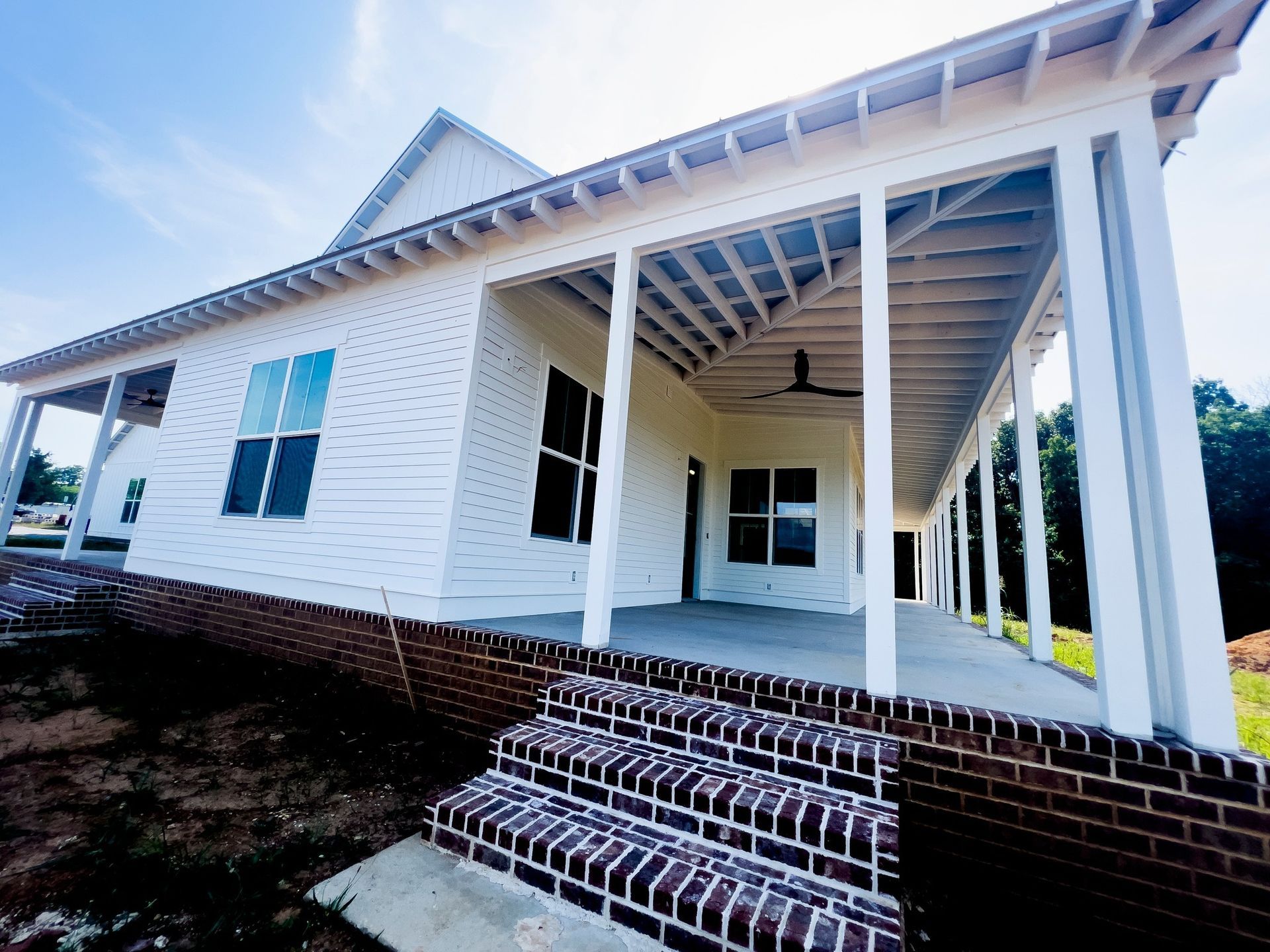 White house with large porch, brick foundation, and steps.