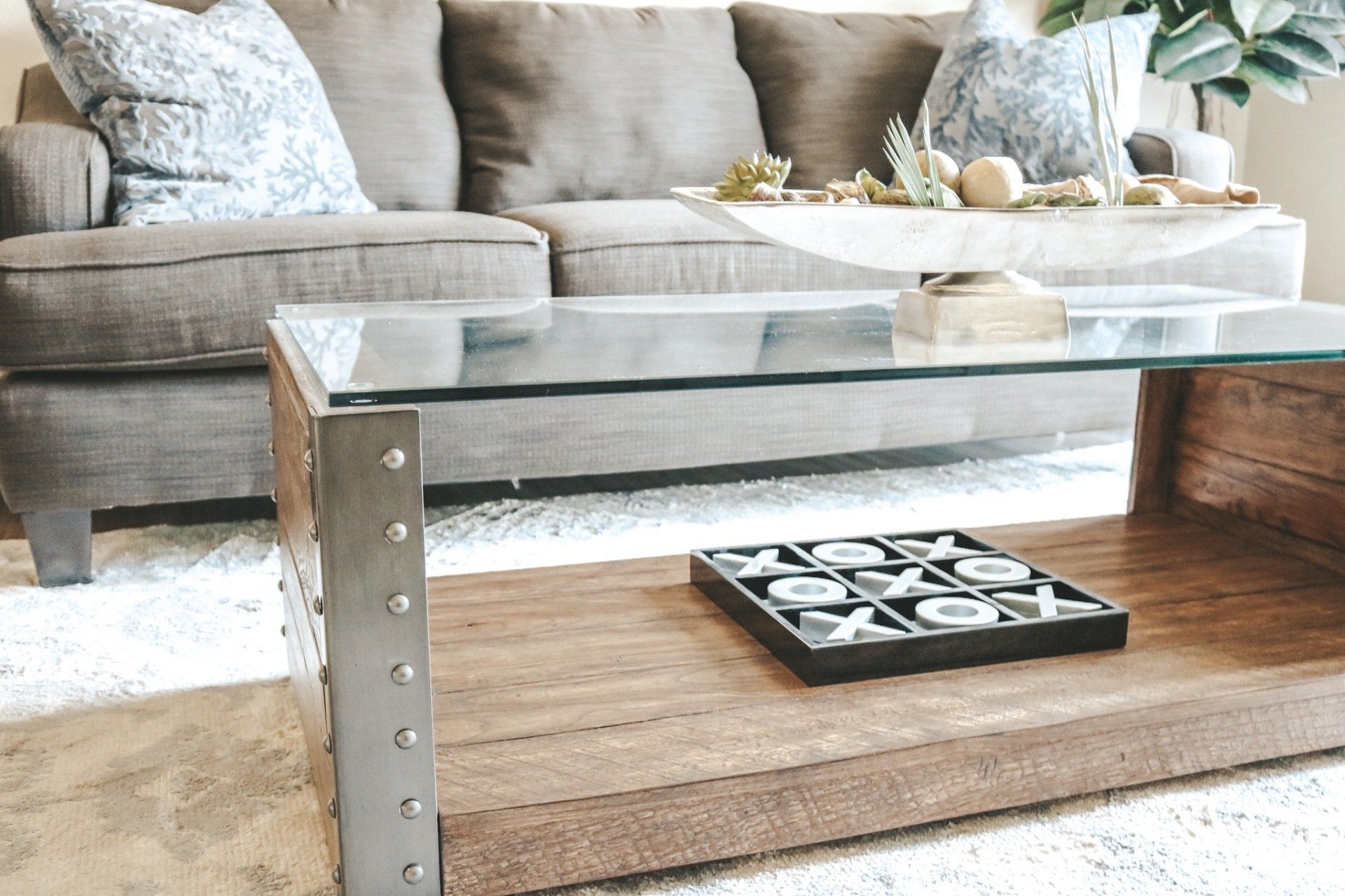 Glass coffee table in a cozy living room with a beige sofa and decorative tray centerpiece