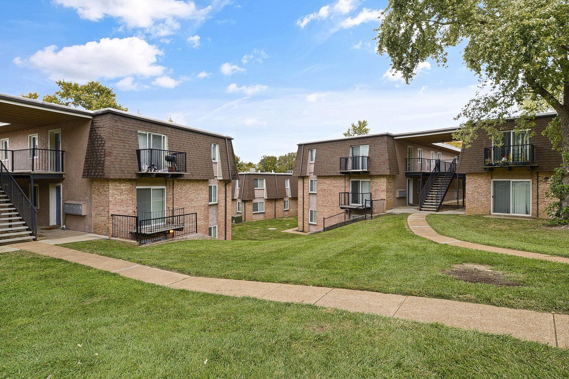 Apartment buildings around a grassy courtyard with a winding path under a blue sky