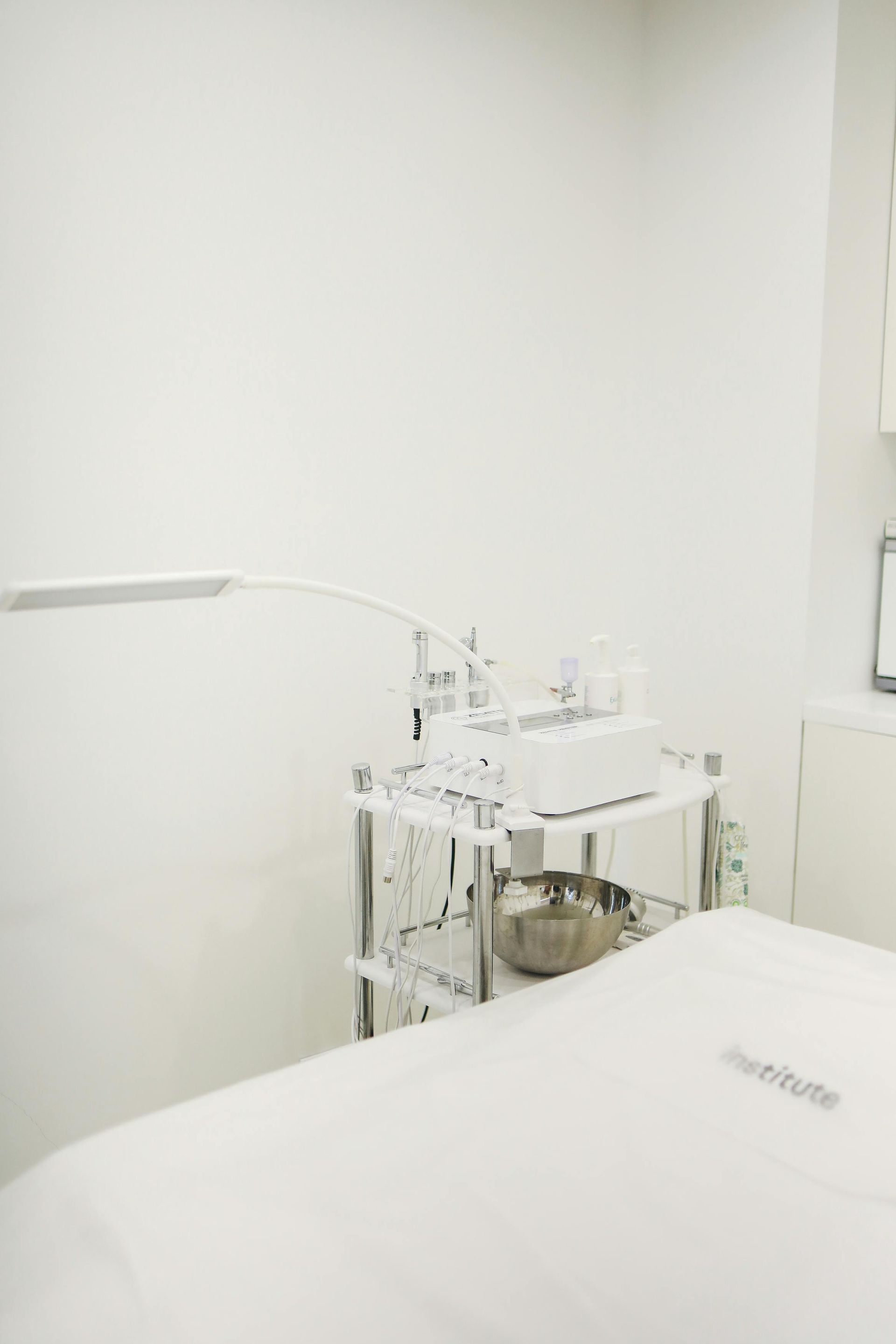 Hospital room with a covered bed and a medical cart holding equipment beside it