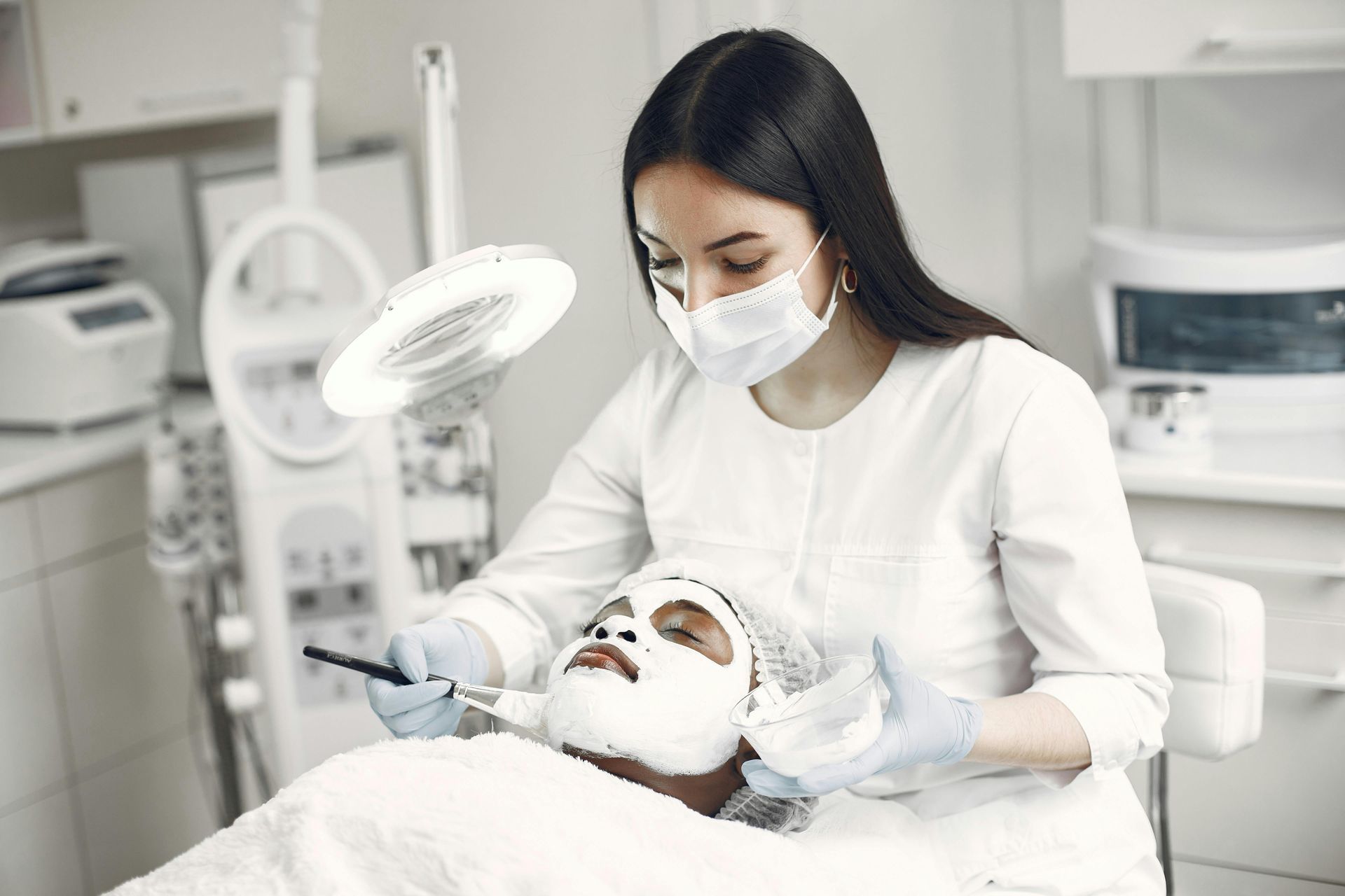 Dental clinician examining a patient in a bright treatment room under a magnifying lamp