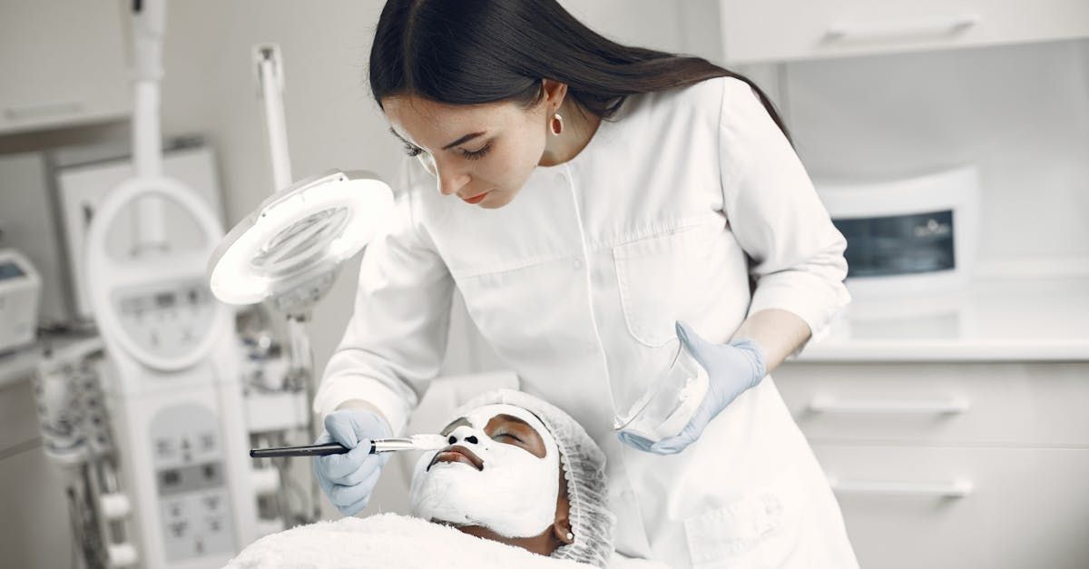 Cosmetologist applying treatment to a client lying on a spa bed in a bright treatment room