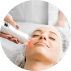 Facial treatment with a handheld device applied to a woman’s face in a spa setting