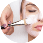Woman applying white facial cream with a brush to her cheek in a skincare close-up