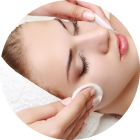 Woman receiving a facial massage with cotton pads on her cheeks, eyes closed, in a spa setting