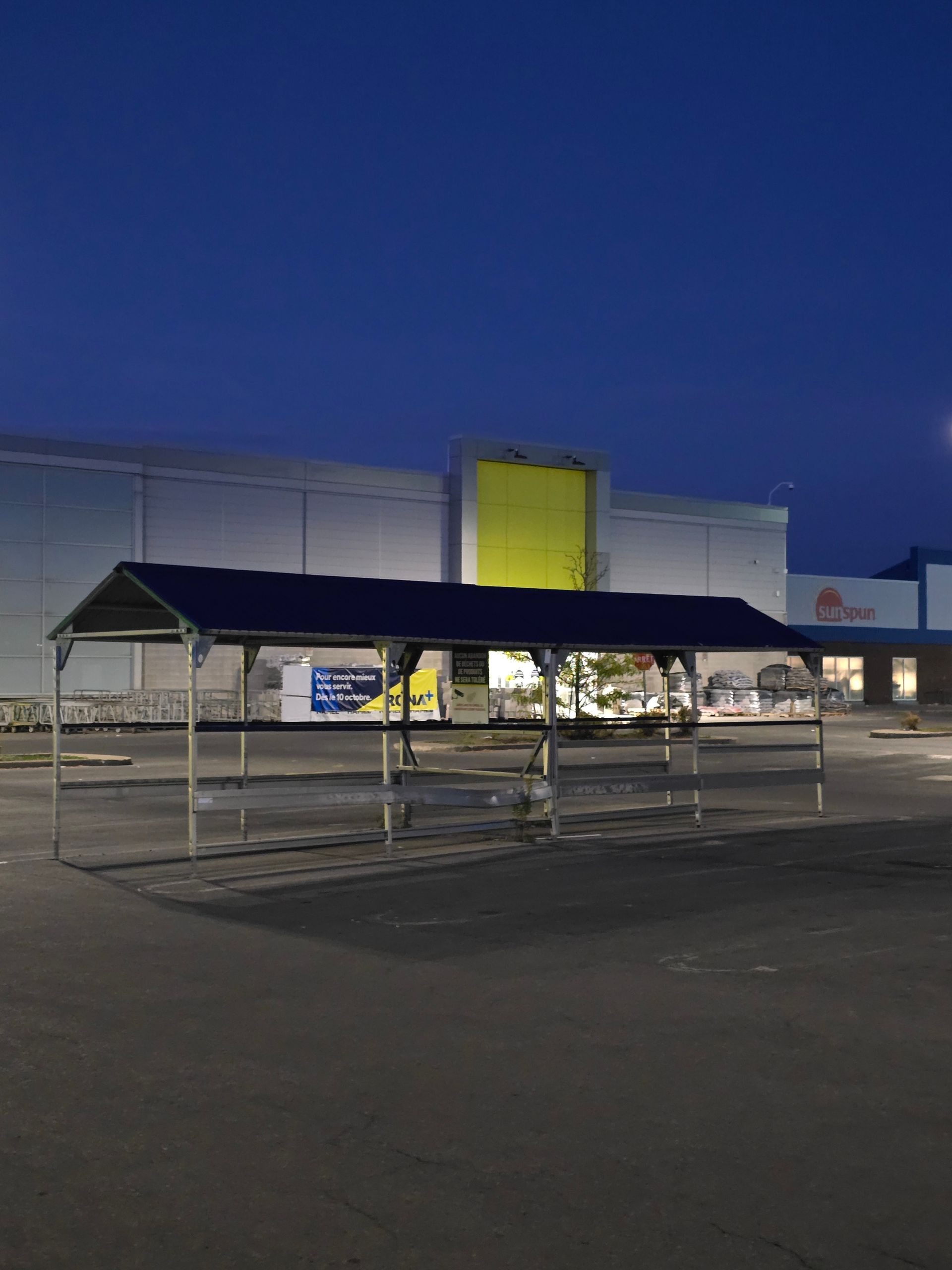 An empty parking lot with a blue canopy in front of a building
