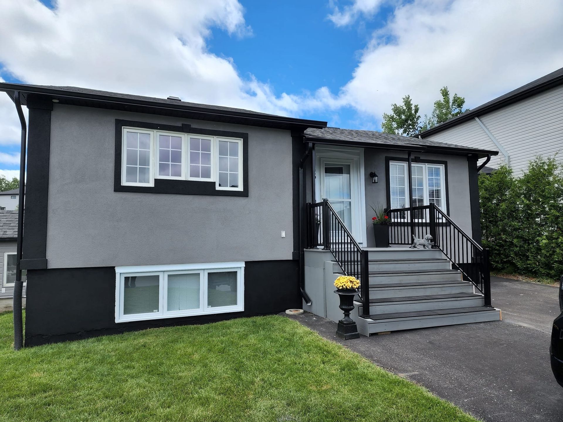 A gray and black house with a car parked in front of it