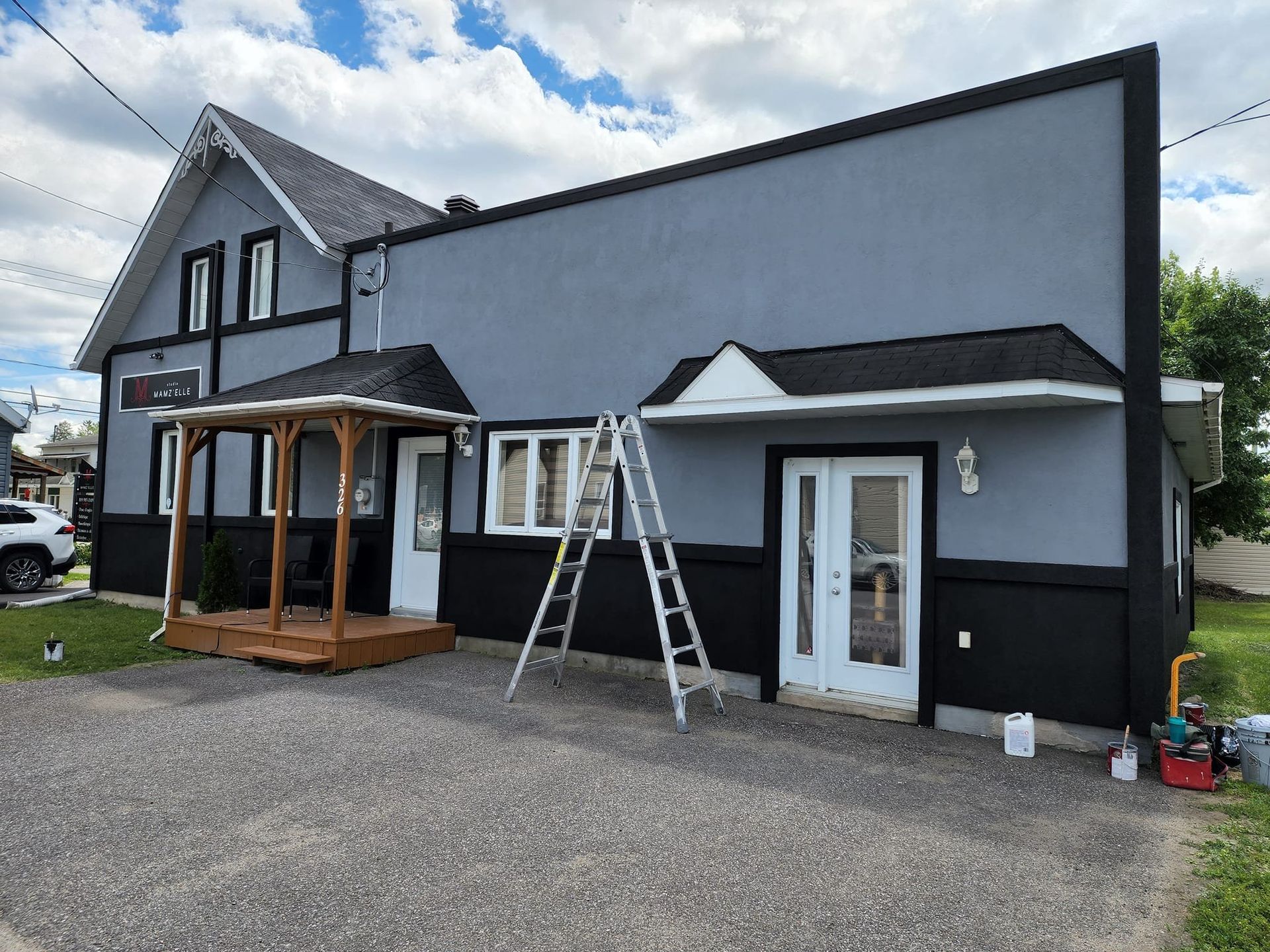 A ladder is sitting in front of a house that is being painted.