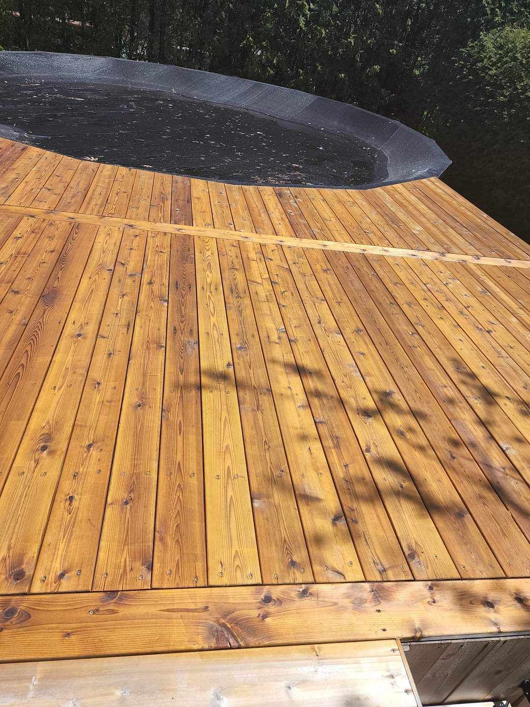 A wooden deck with a swimming pool in the background.