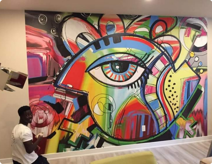 A man is standing in front of a colorful painting on a wall