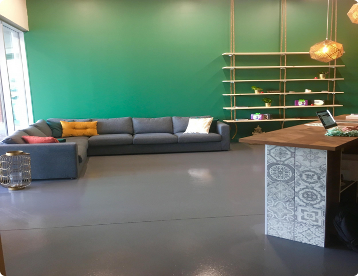 A living room with a couch and a desk with a laptop on it.