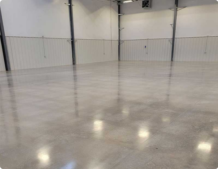 A large empty room with a concrete floor and white walls