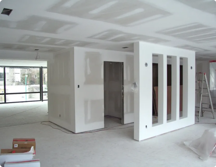 An empty room with a ladder and boxes on the floor