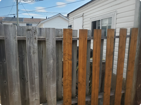 A wooden fence with a white house in the background
