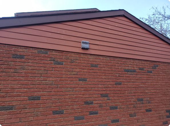 A red brick building with a brown roof and siding