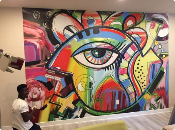 A man is standing in front of a colorful painting of an eye