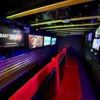 Dark movie theater aisle with red seats, multiple screens, and neon lighting