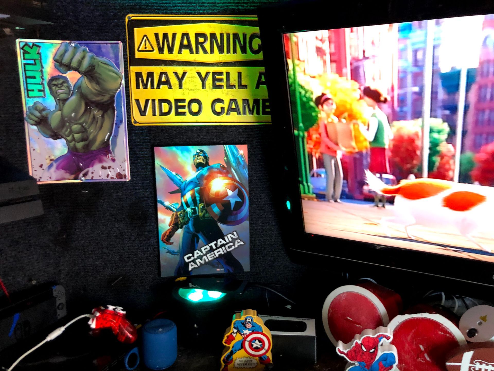 Video game display with a warning sign, character art, and colorful arcade prizes beside a lit screen