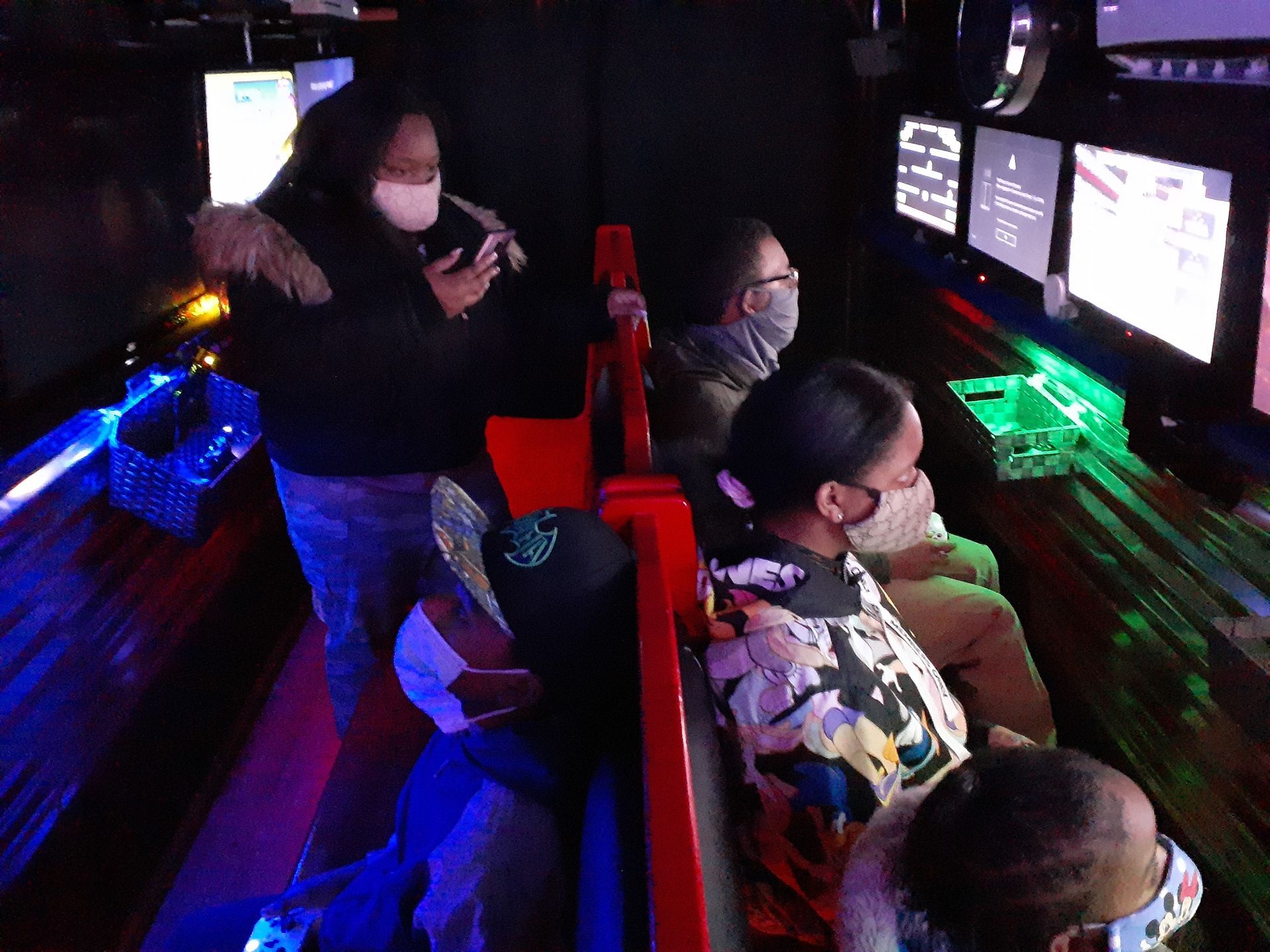 People seated at glowing gaming monitors in a dark arcade or computer lab