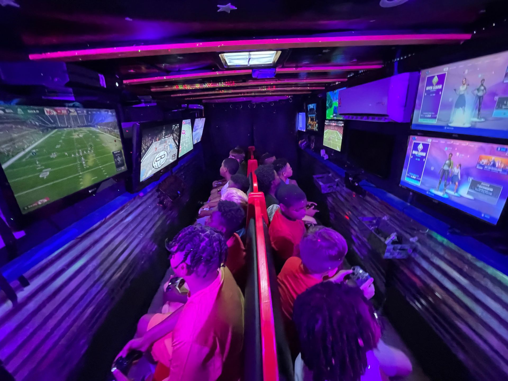 People watching multiple football games in a neon-lit sports viewing room