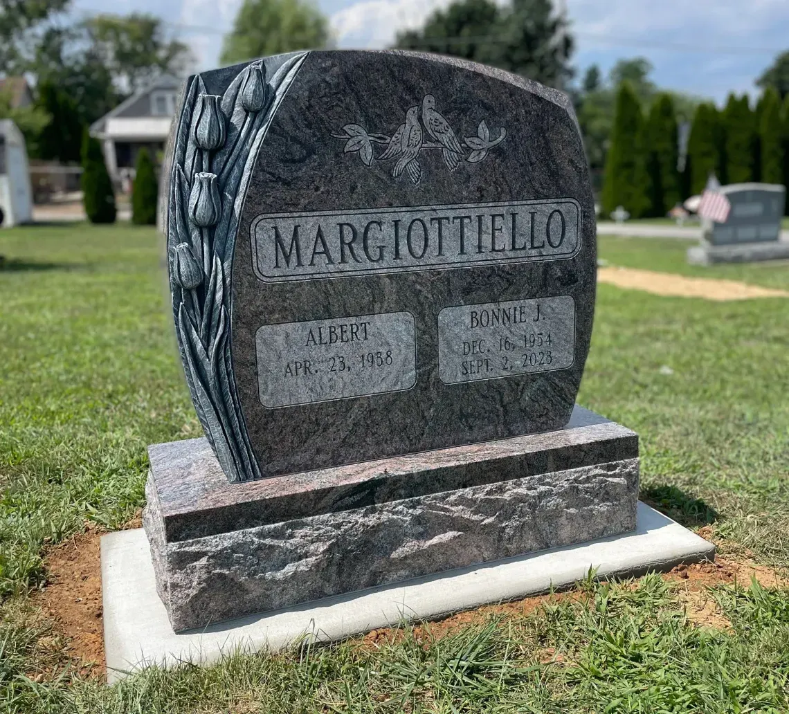 A dark granite tombstone with the name 