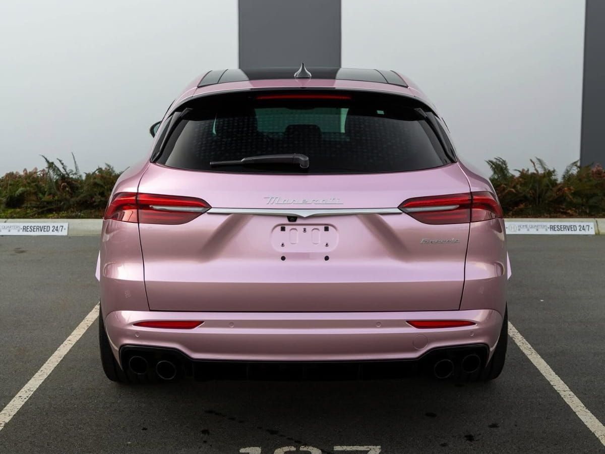Rear view of a pink SUV parked in an outdoor parking space.