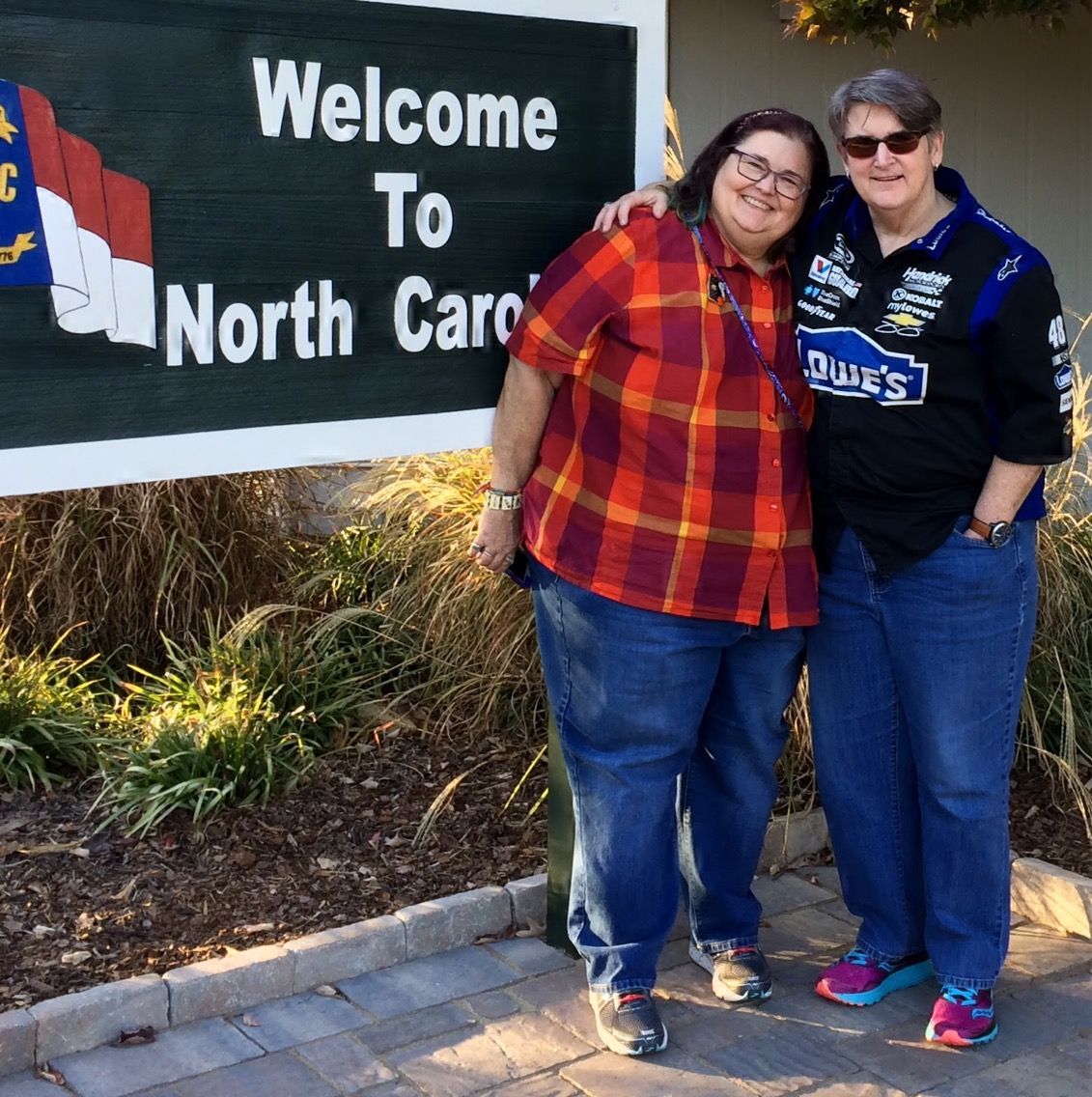 Two people standing together smiling in front of a 