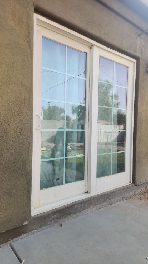 White sliding glass doors with grid design set in stucco wall.