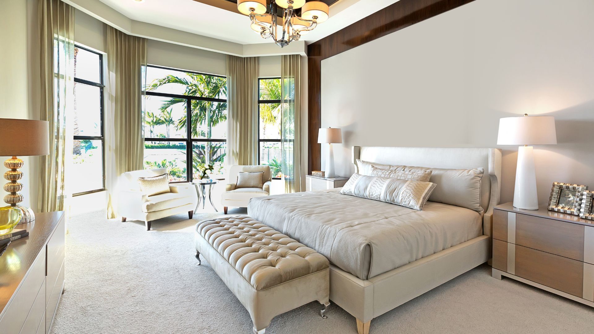 Bright modern bedroom with a tufted bed, bench, large windows, and bedside lamps