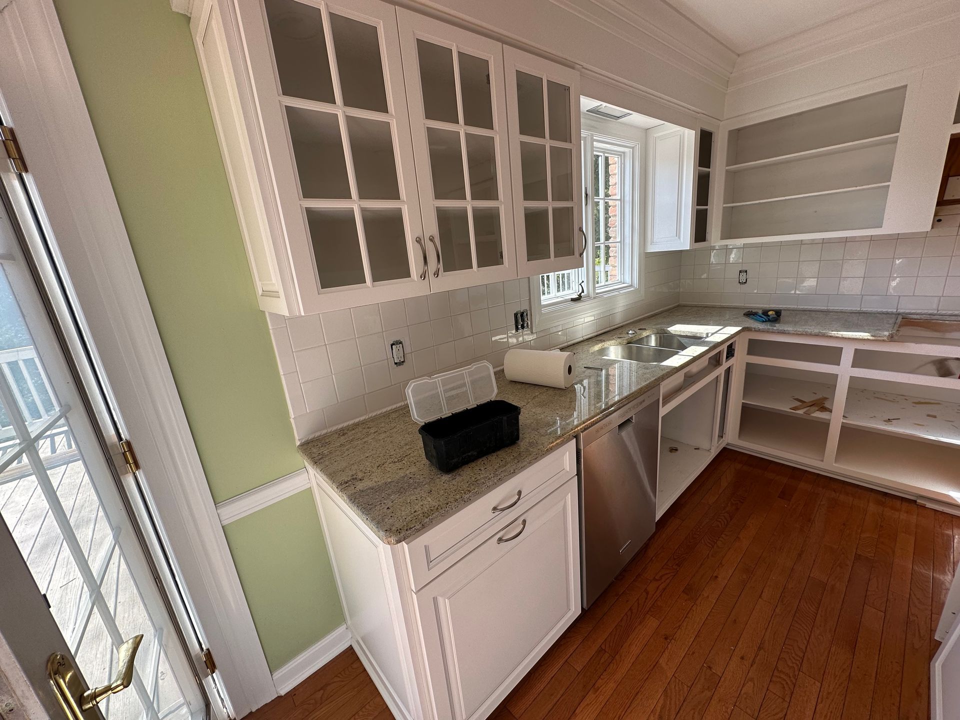 Kitchen under renovation with covered countertops, taped cabinets, and protective floor covering