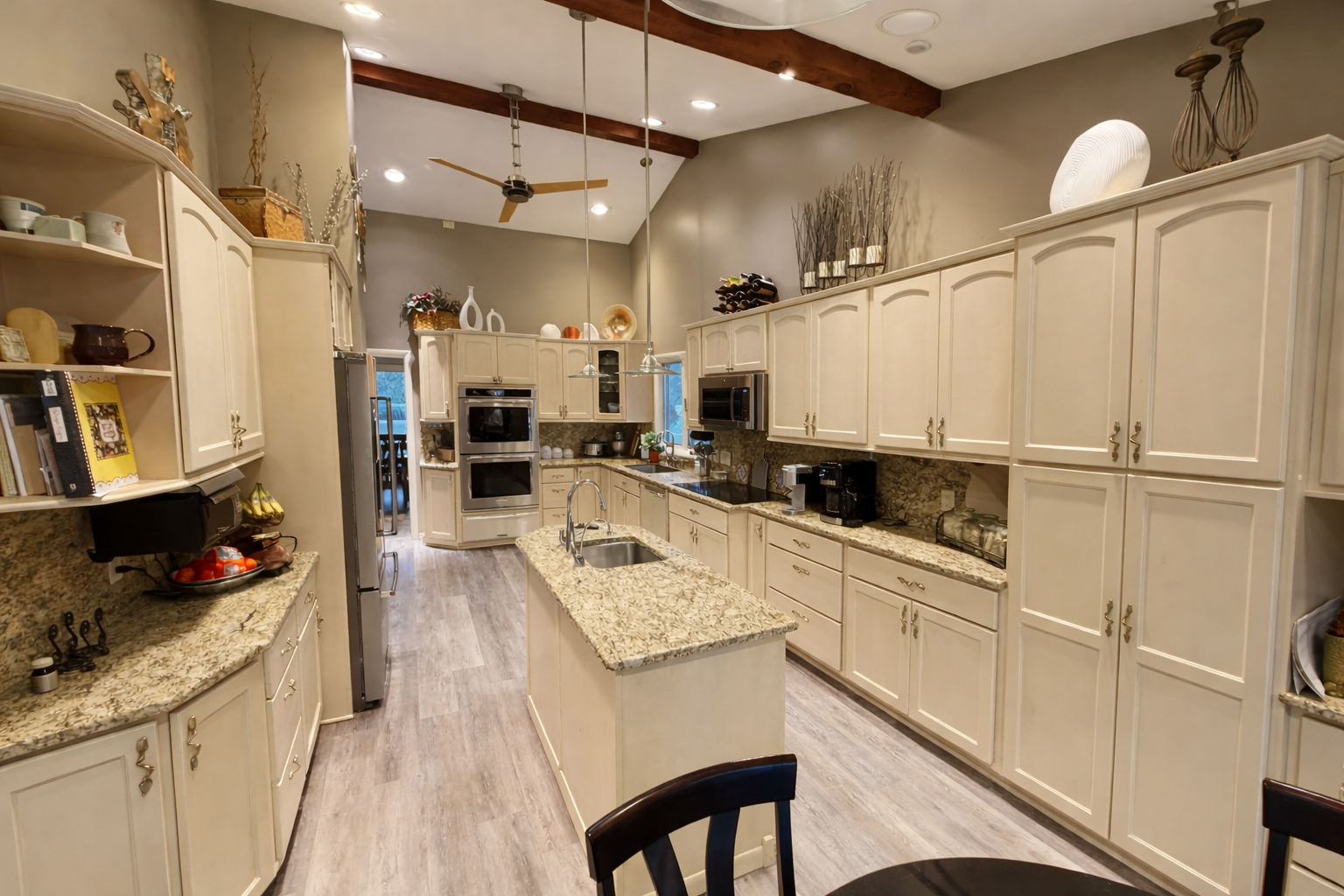 Bright white modern kitchen with a long marble island, dark wood floors, and built-in appliances.