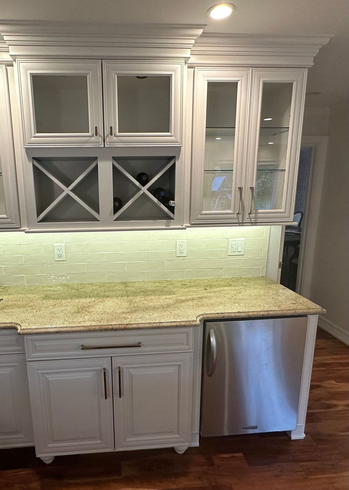 Small bathroom vanity with wood cabinets, white countertop, gold faucet, and green towels.