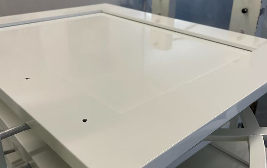 White adjustable standing desk in an office-like space with a glossy tabletop and metal frame