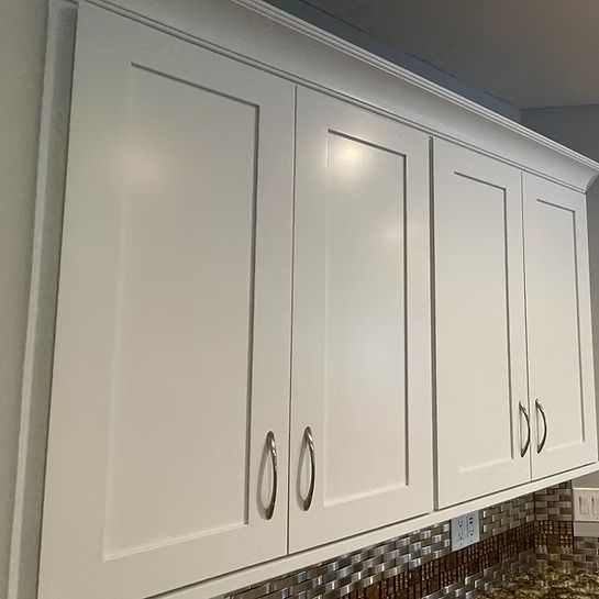 White kitchen cabinets with brushed metal handles above a tiled backsplash.