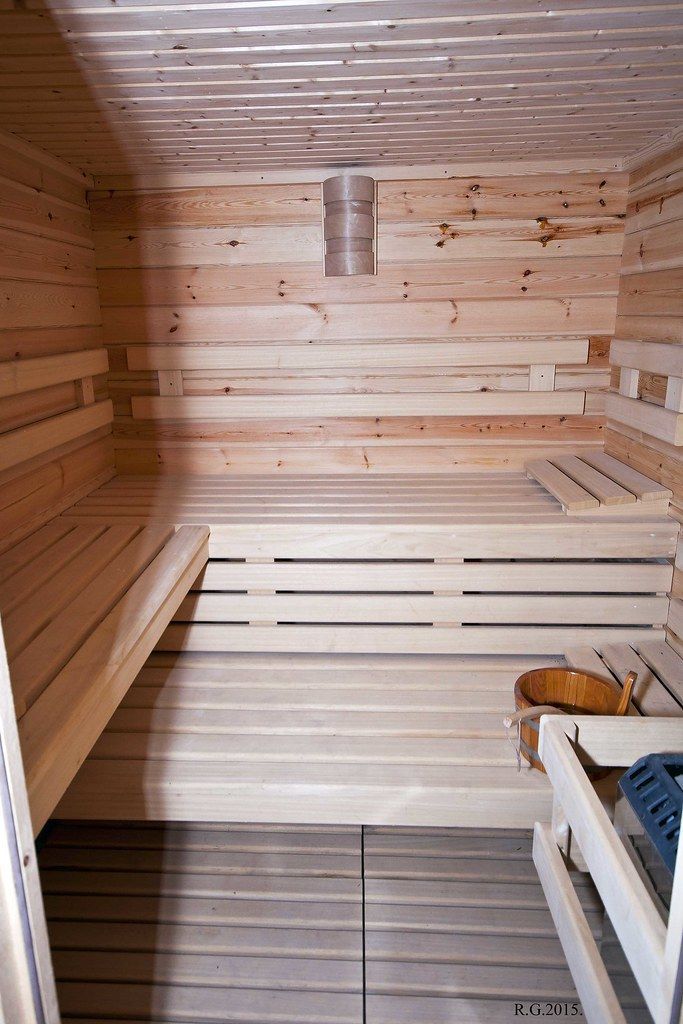 Wood-paneled sauna interior with bench seating and slatted floor, viewed from the doorway
